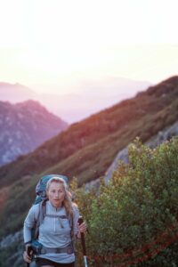 femme pratiquant la marche nordique sur le flanc d'une montagne au coucher de soleil