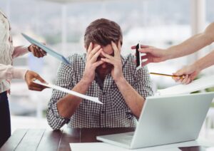 homme stressé derrière son bureau la tête dans les mains